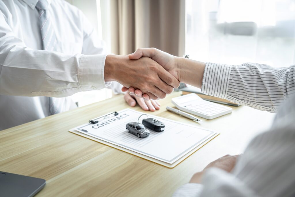 Insurance agent and customer shake hands after discussing car insurance for older cars.