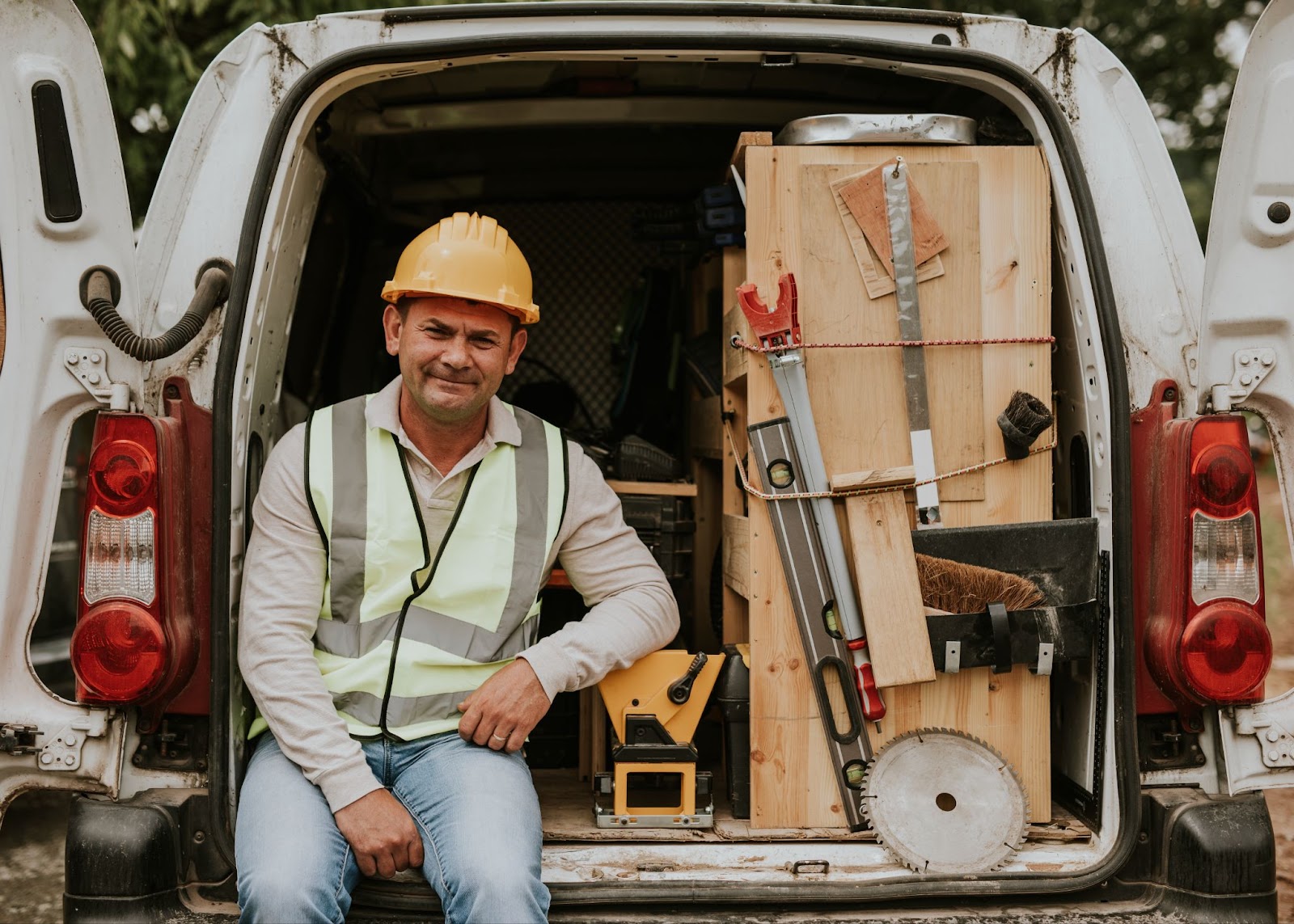 contractor sitting in back of open van filled with tools