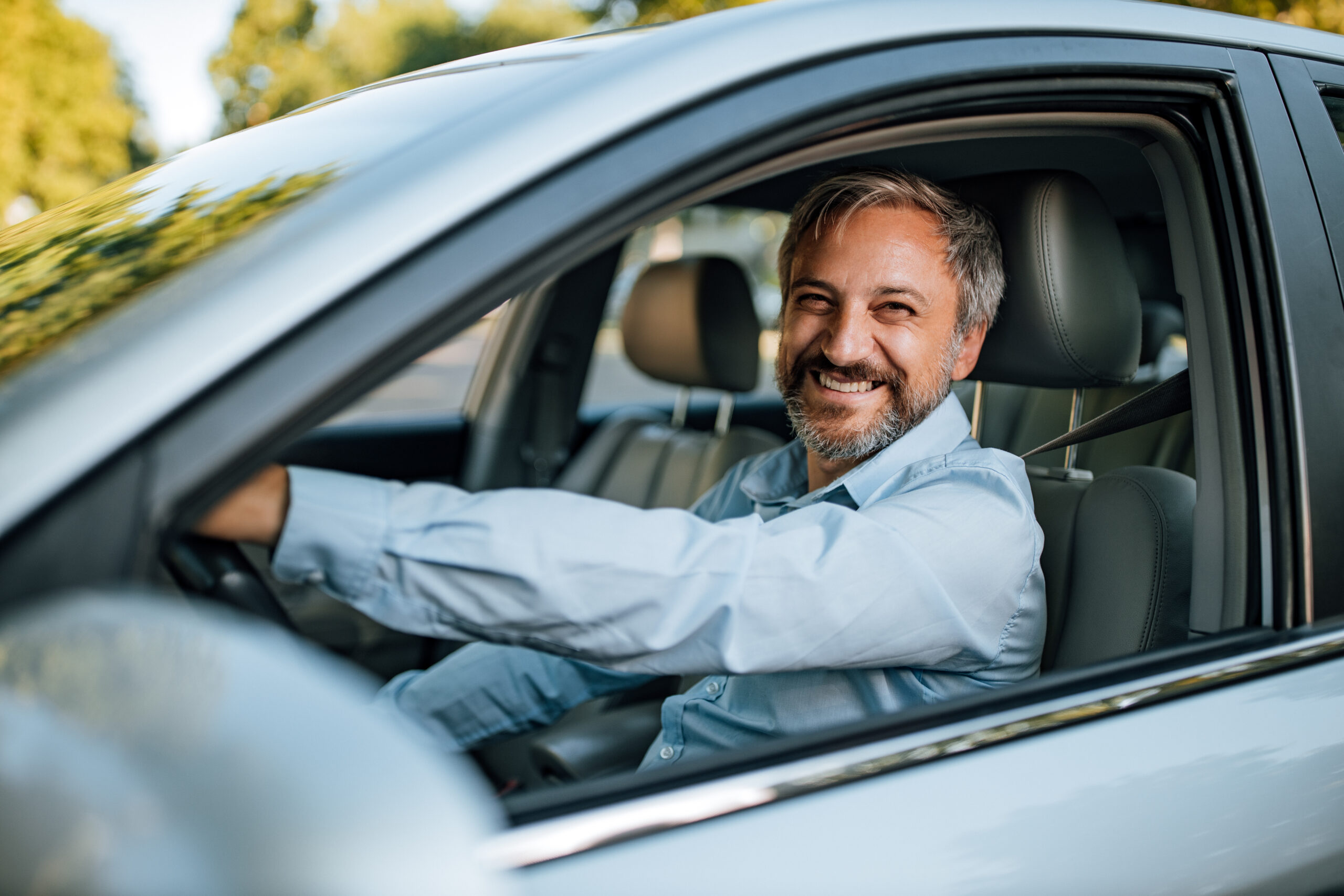 smiling man in driver's seat of car