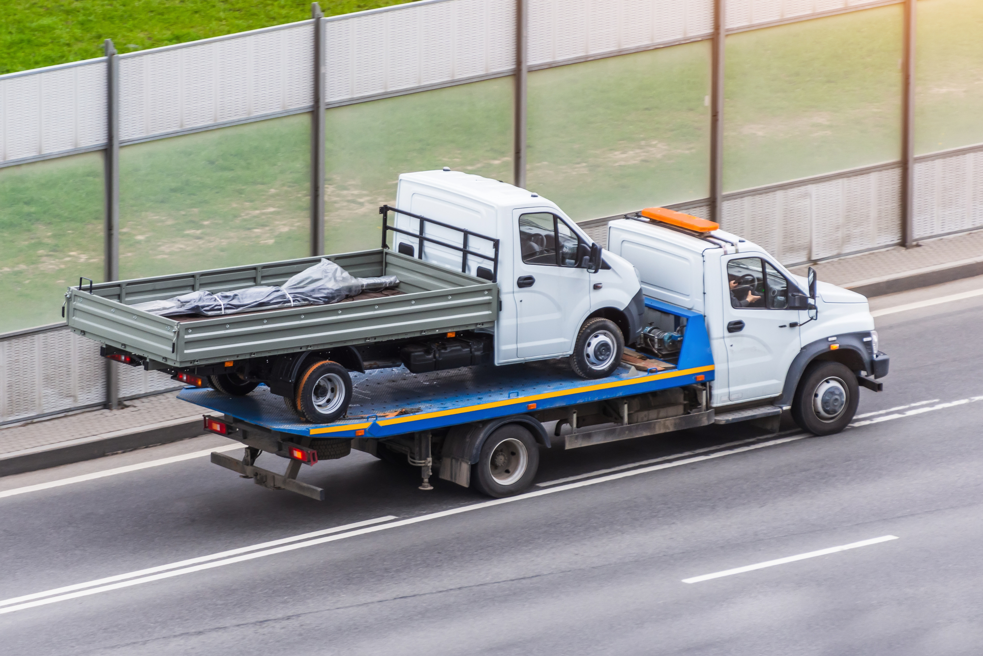 Tow truck transporting another commercial truck on the road