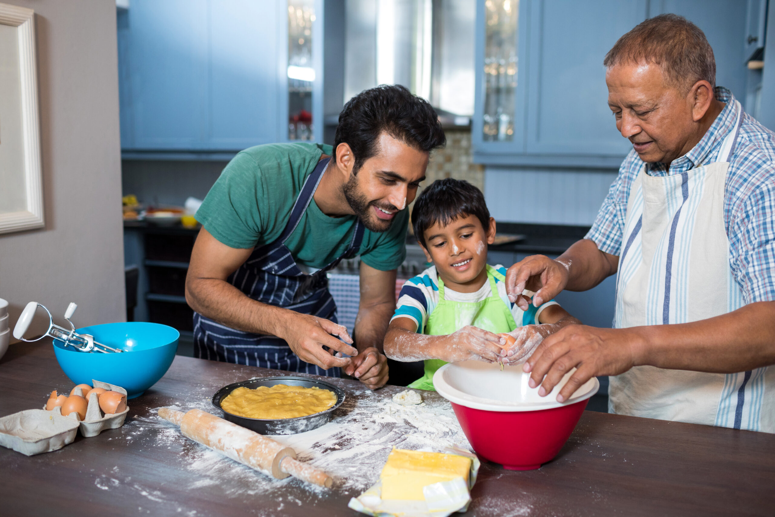 Young boy cooking with father and grandfather