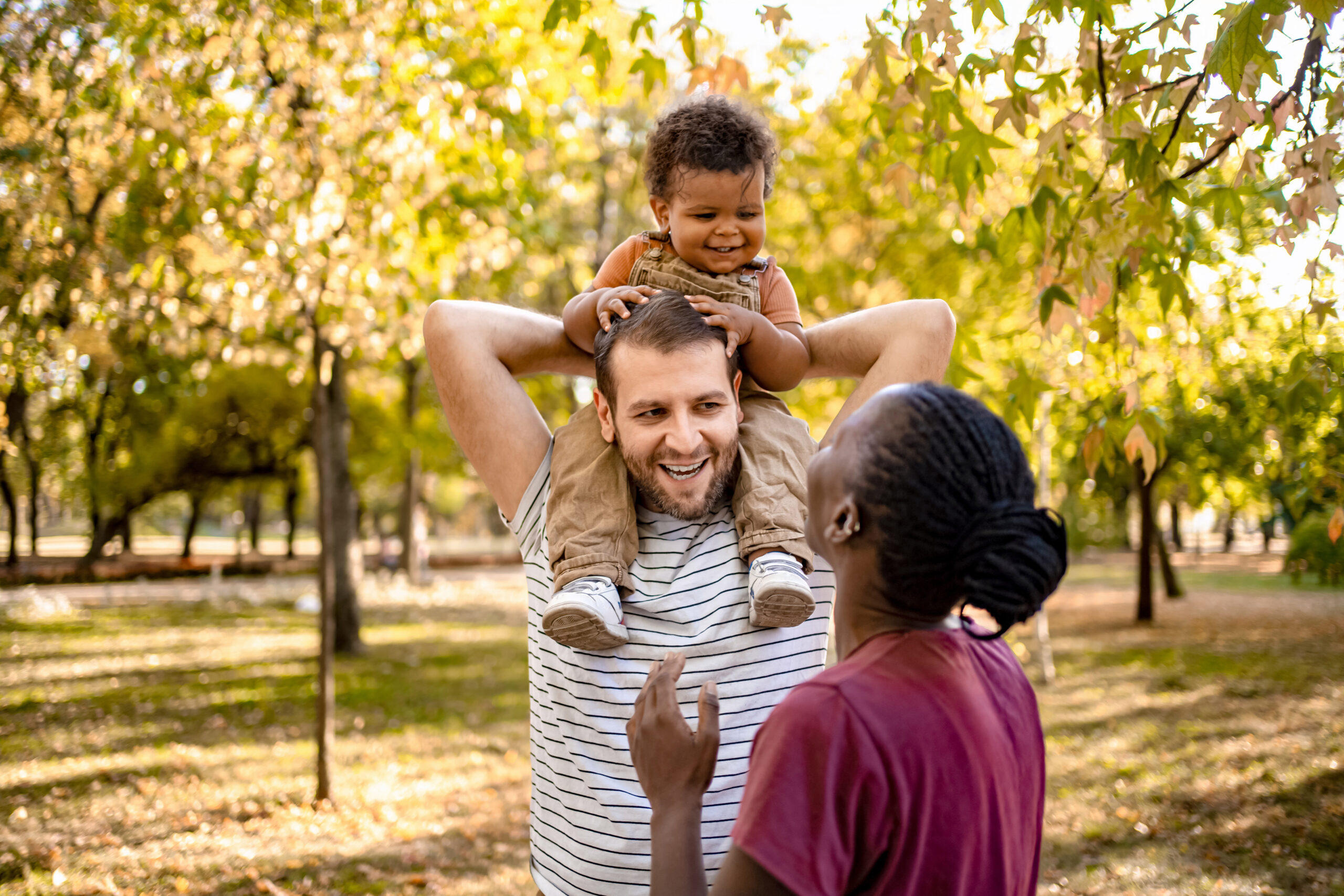 couple outside with baby on dad's shoulders