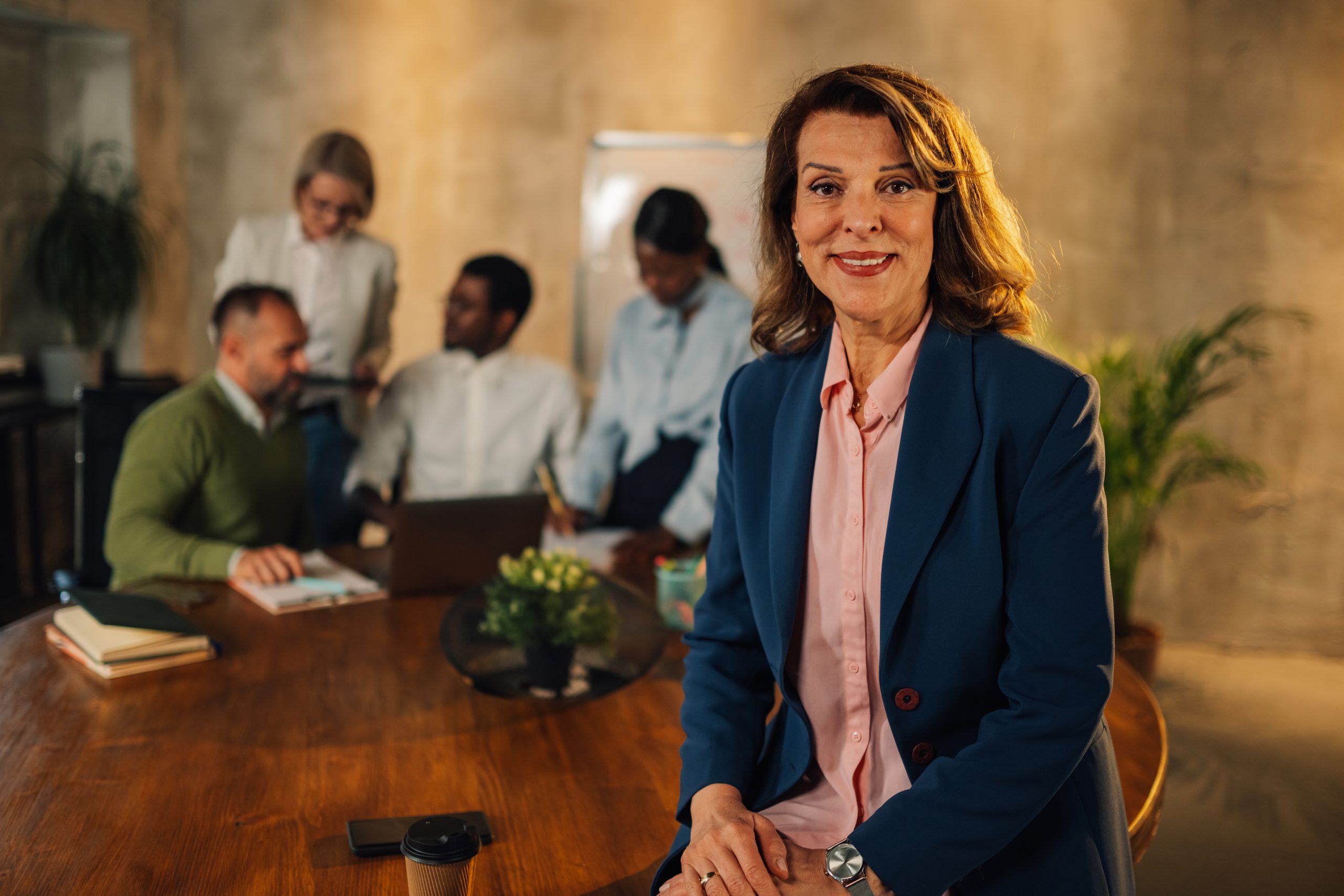ceo sitting on table with team behind her
