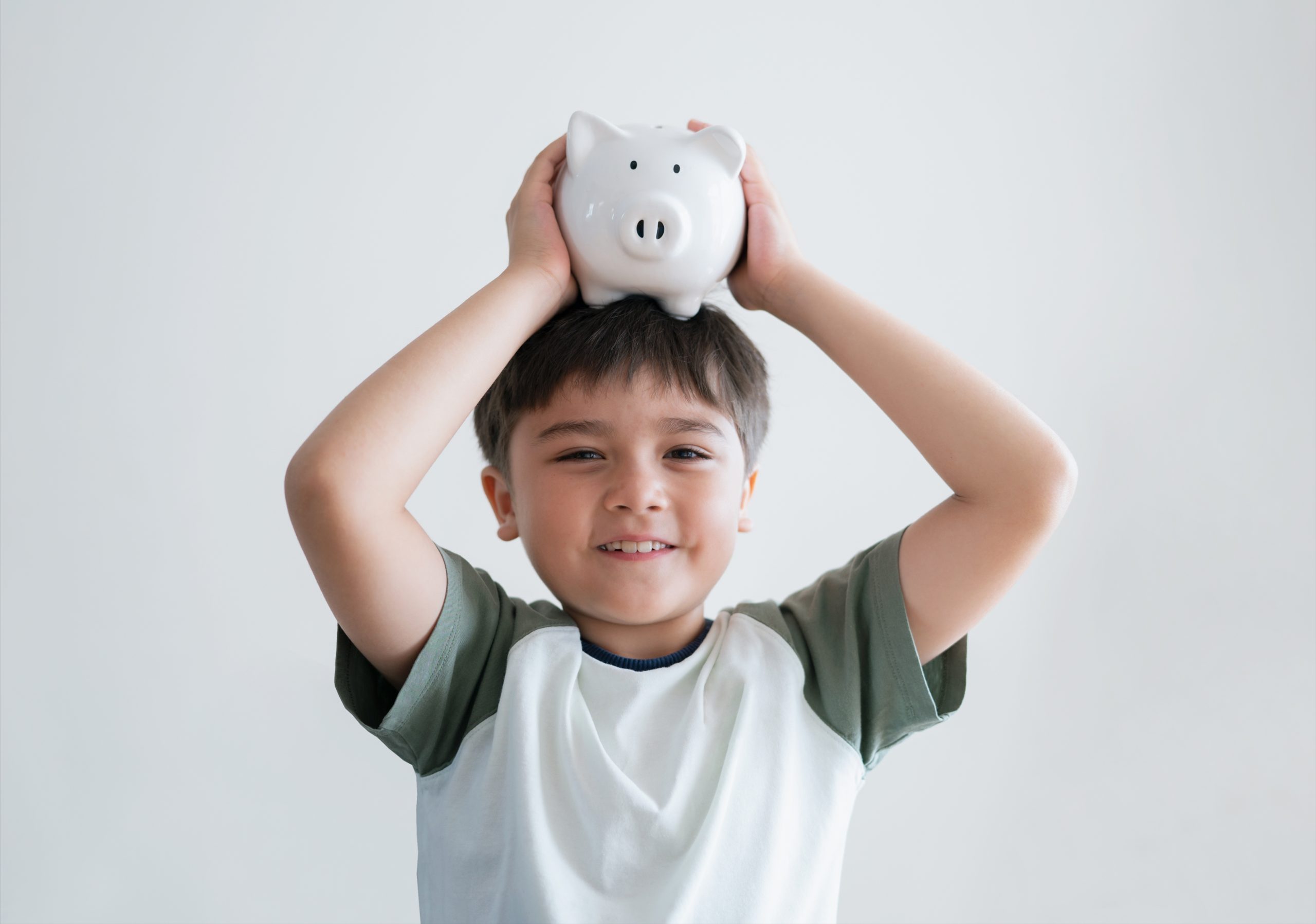 young boy holding white piggy bank on his head