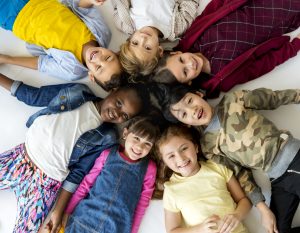 young children lying on ground in a circle with their heads together