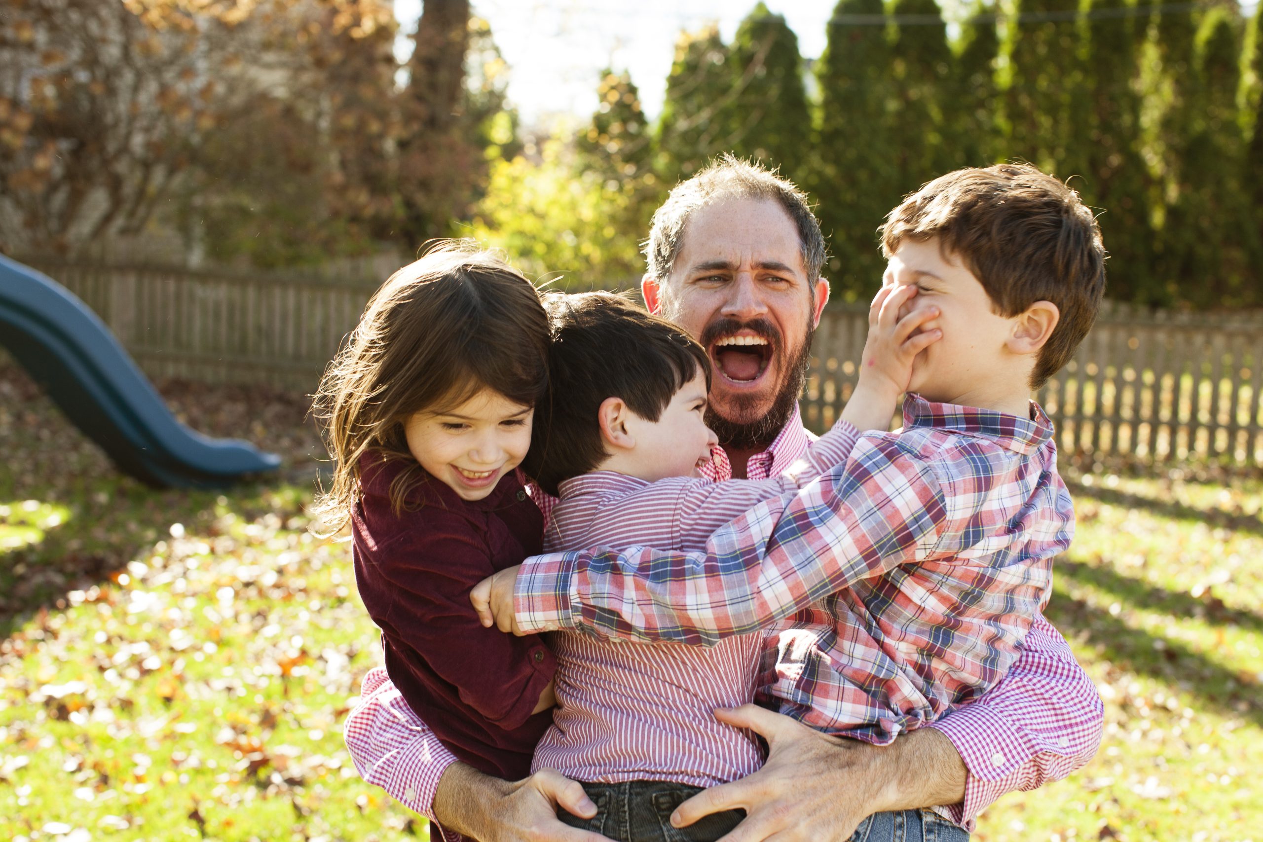 dad playing with children in backyard