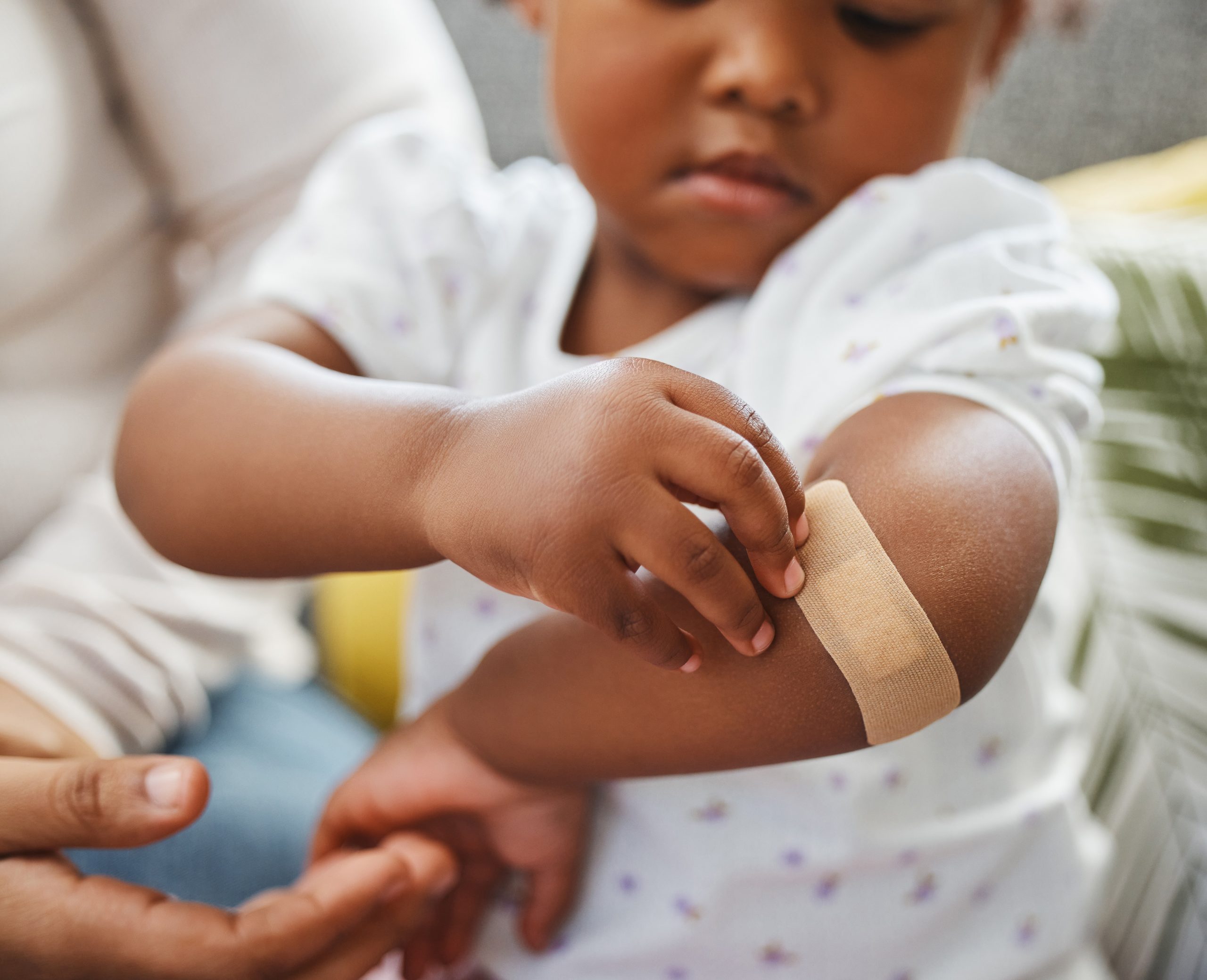 toddler putting bandaid on elbow