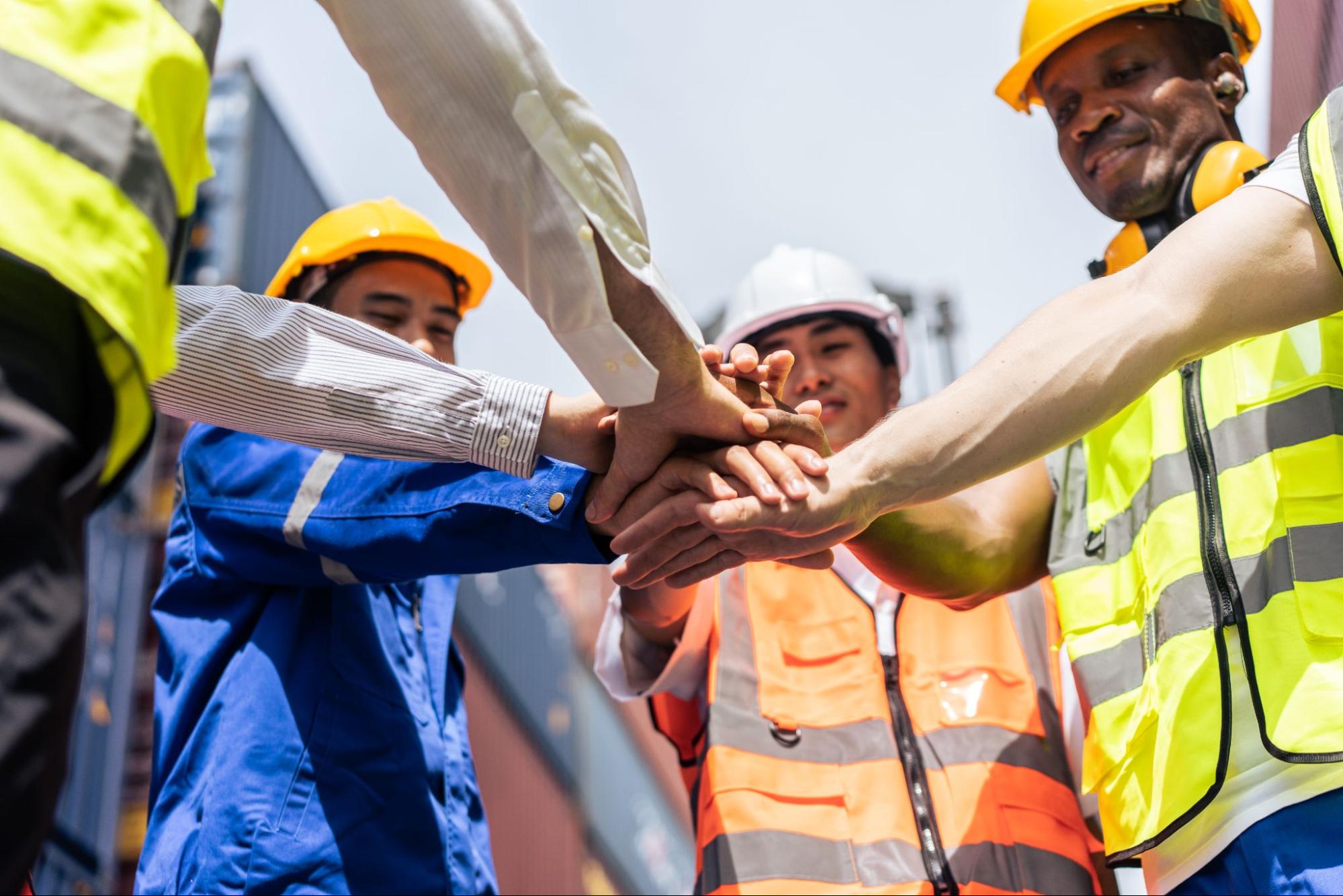 construction team joining hands in middle of circle