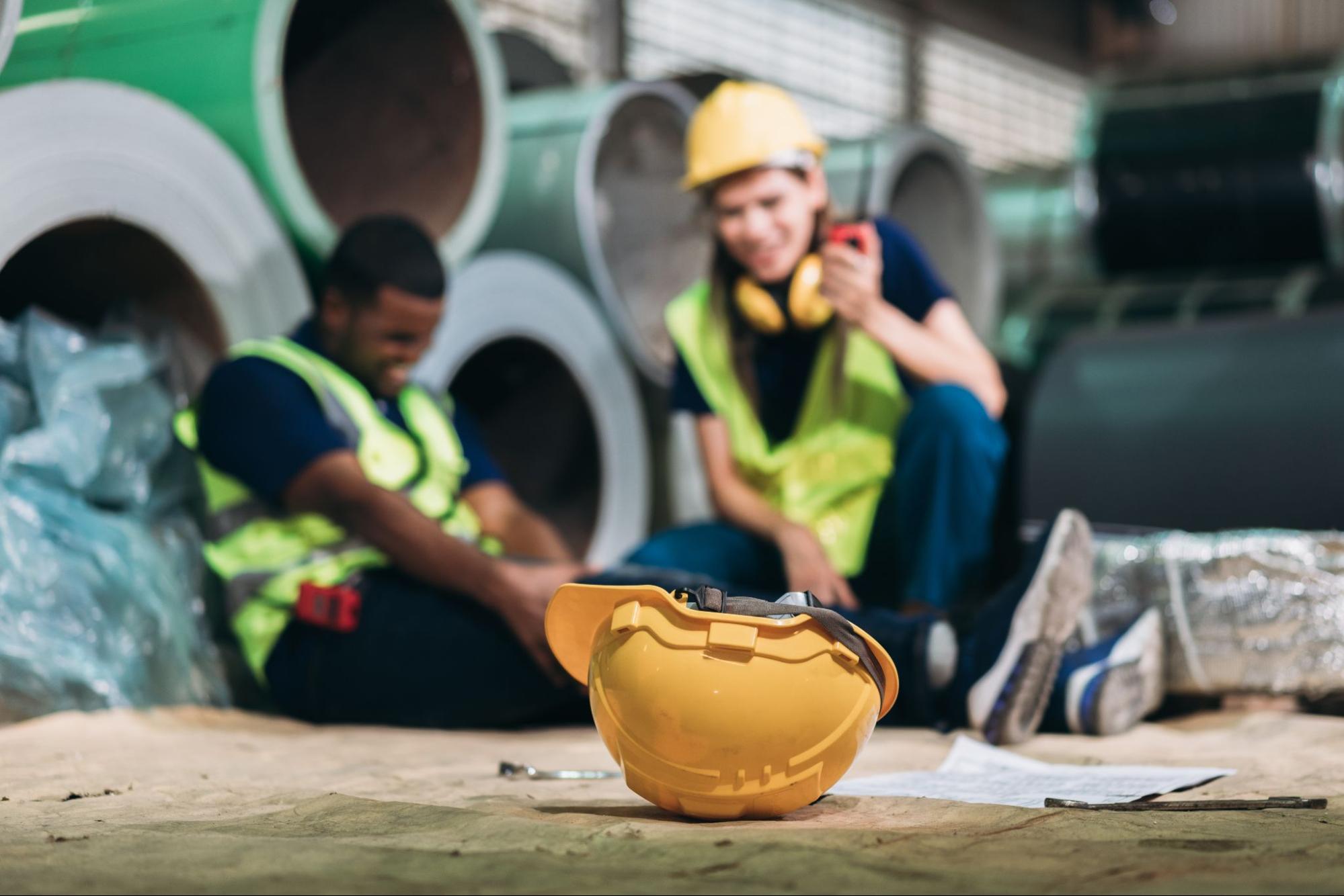 hardhat on ground with injured worker in background