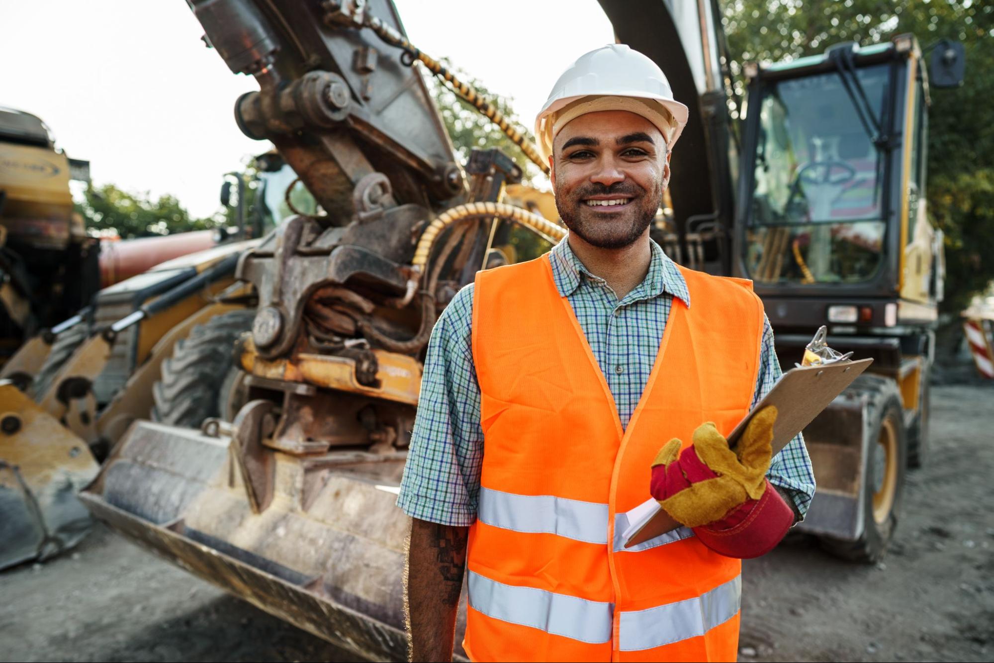 man in reflective vest and hard hat in front of machine