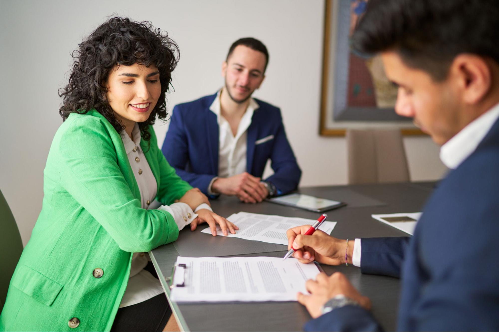 man signing document while coworkers watch